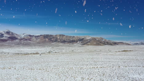 Winter-desert-and-mountain-range-during-snowfall,-aerial-fly-forward-view