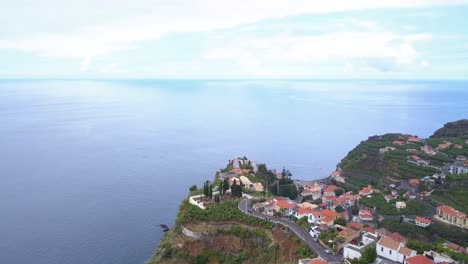 Drone-shot-overhead-Ponta-Do-Sol-village-looking-out-over-Atlantic-Ocean-coastline