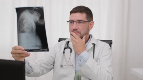 Doctor-Sitting-Inside-His-Office-And-Reading-The-X-Ray-Plate-Of-The-Patient