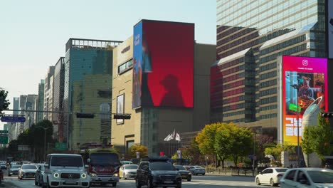 Cars-traffic-on-multilane-Teheran-ro-Road-in-Seoul-near-Grand-Intercontinental-Hotel-COEX-and-Hyundai-Department-Store,-next-to-Samseong-Station-in-Autumn,-Huge-Outdoor-Wall-Ad-Billboards-at-sunset