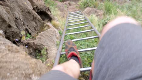 A-point-of-view-shot-of-a-man-legs-climbing-down-a-ladder-on-a-rural-mountain-climb-in-Africa