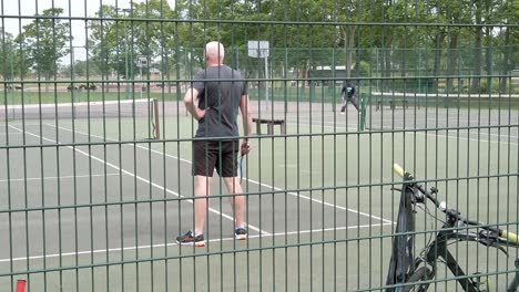 Slow-motion-senior-practice-tennis-on-court-suburban-public-playground