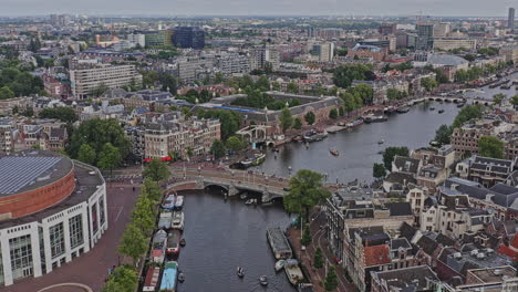 Amsterdam-Niederlande-Luftbild-V40-Drohne-Fliegt-Entlang-Des-Berühmten-Flusses-Amstel-Mit-Booten,-Die-Auf-Dem-Wasserkanal-Und-über-Die-Blauwbrug-Brücke-Durch-Die-Viertel-Jodenbuurt-Und-Grachtengordel-Fahren---August-2021