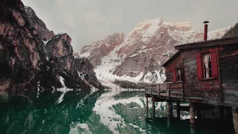 Wooden-hut-on-a-turquoise-lake-surrounded-by-mountains