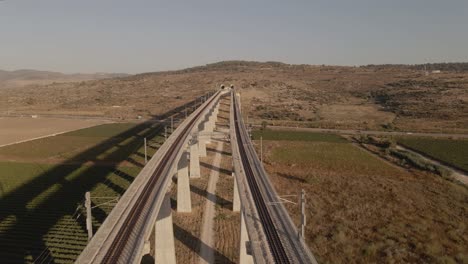 Railroad-track-on-a-bridge-over-a-valley-leading-through-the-terrain-of-a-hill-in-Israel-in-sunny-autumn