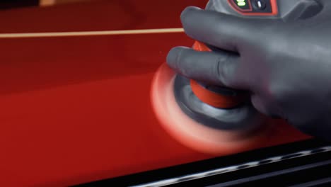 Close-up-of-a-man-with-black-latex-gloves-polishing-red-paint-with-a-small-polishing-machine