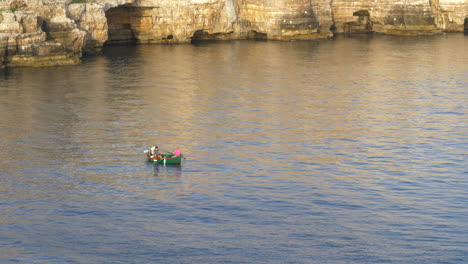 Fishermen-On-A-Small-Boat-Floating-On-The-Adriatic-Sea-In-Polignano-a-Mare,-Apulia,-Italy