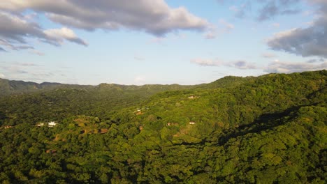 Aerial-video-of-rising-movement-above-the-thick-and-lush-rainforest-near-the-pacific-shore-during-vibrant-sunset
