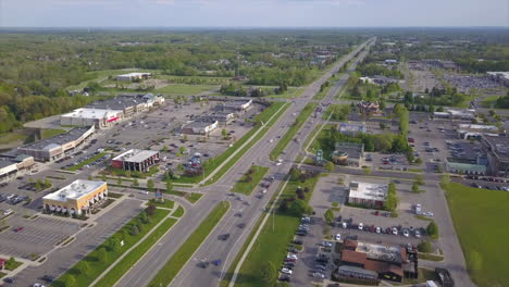 Aerial-drone-shot-of-a-busy-divided-highway-in-a-suburban-area-with-shopping