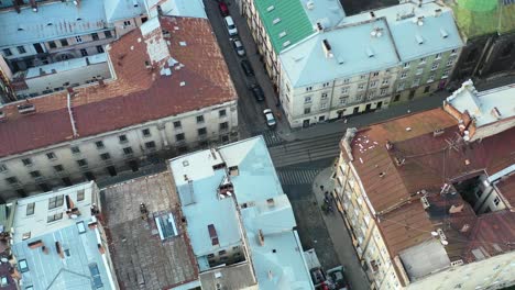 Aerial-of-European-buildings-and-people-walking-the-streets-of-Lviv-Ukraine-with-cars-parked-on-the-road