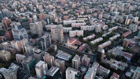 Aerial-orbit-of-buildings-and-Divina-Providencia-church-in-residential-neighborhood-at-golden-hour,-Santiago-city,-Chile