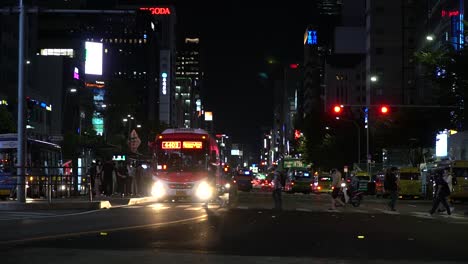 Many-People-wearing-protective-face-masks-during-covid-19-pandemic-crossing-the-road-in-Gangnam-Street-Bus-Stop-at-nighttime-Seoul,-South-Korea