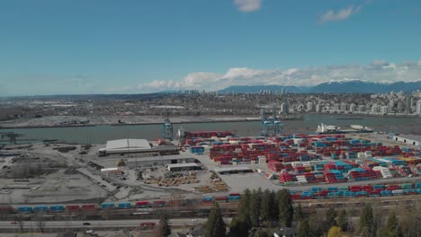 colorful-shipping-containers-stacked-high-and-organized-at-busy-city-port-harbor-dock-on-edge-of-fraser-river-in-Surrey-BC-near-Delta-BC-in-Canada-Aerial-wide-ascending