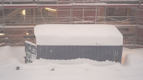 Container-Mit-Offener-Tür-Auf-Der-Baustelle,-Bedeckt-Mit-Riesigen-Mengen-Schnee-–-Gebäude-Im-Bau-Mit-Gerüst-Im-Hintergrund-–-Statischer-Clip-Bei-Verschneitem-Wetter-Myrkdalen-Norwegen