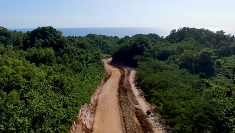 Gravel-layer-built-of-highway-road-winding-through-Indonesia-jungle,-aerial-view