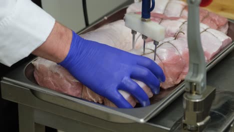 Video-of-seasoning-of-raw-pork-meat-loin-by-a-chef-wearing-blue-gloves-in-the-kitchen