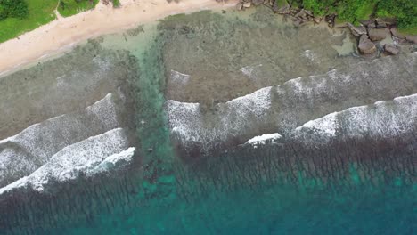 Spectacular-top-down-view-aerial-shot-capturing-beautiful-turquoise-sea-water-with-waves-crashing-the-rocky-shore-at-Houshi-Fringing-Reef,-Xiaoliuqiu-Lambai-Island,-Pingtung-county,-Taiwan