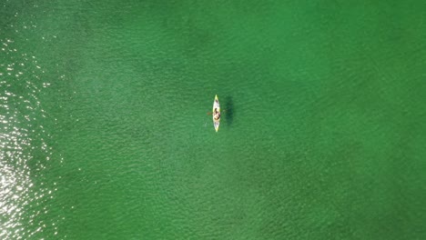 Vista-De-Arriba-Hacia-Abajo-De-La-Persona-En-Kayak-En-El-Lago-Con-Aguas-Verdes-Tranquilas-En-Verano