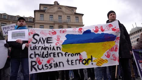 Save-Ukrainian-children-from-Russia-is-written-on-a-banner-at-peace-rally-in-Munich-after-Russia-invades-Ukraine