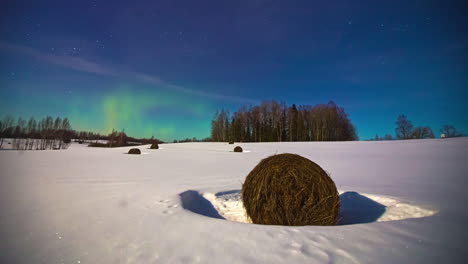 Weitwinkelaufnahme-Eines-Verschneiten-Winterfeldes-Mit-Gefrorenen-Heuballen-Und-Magischer-Aurora-Borealis-Am-Hellen-Nachthimmel-–-Zeitraffer