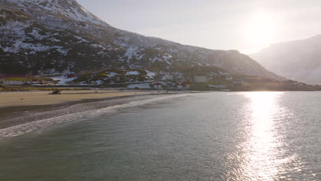 Drone-flight-along-beach-in-Grotfjord,-reflection-of-sunset