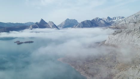 Drone-camera-flyng-towards-a-mist-cloud-above-a-lake-in-León,-Spain
