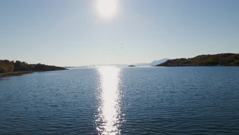 Reiher-Fliegen-über-Wasser,-Das-Sonnenlicht-Reflektiert,-Auf-Der-Insel-Senja,-Norwegen-–-Luftdrohnenaufnahme
