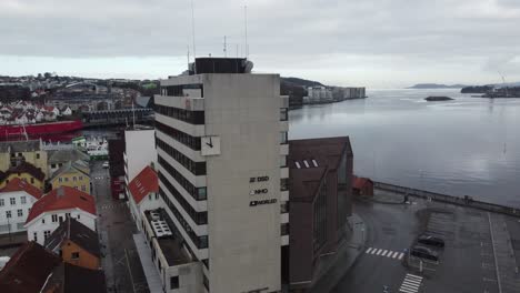 Tall-Norled-AS-office-building-in-Stavanger---Slow-moving-reverse-aerial-with-vagen-fjord-in-background