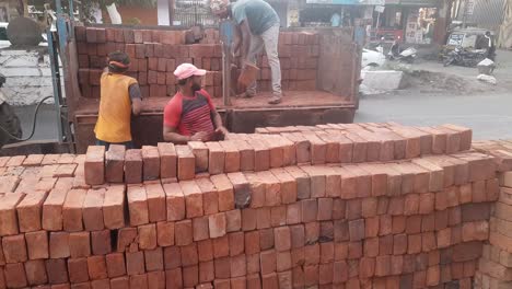 An-Indian-labors-are-unloading-red-bricks-from-the-tractor-trolley-at-construction-site