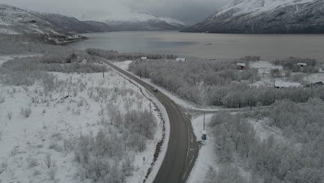 Conducción-De-Automóviles-En-Una-Carretera-Aislada-Con-Un-Denso-Bosque-Con-Vistas-Al-Lago-Durante-El-Invierno-Nevado