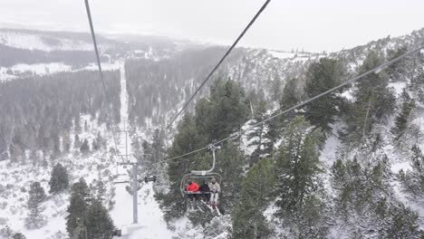People-riding-ski-lift-in-High-Tatras-mountains-resort-at-snowfall---pov
