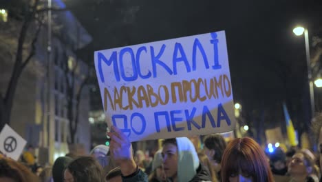 2022-Russia-invasion-of-Ukraine---protester-holding-a-plaque-"Moscow-please-go-to-hell"-at-an-anti-war-demonstration-in-Warsaw-on-the-very-first-day-of-the-war
