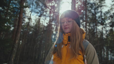 Young-woman-hiking-in-forest-on-a-sunny-winter-day