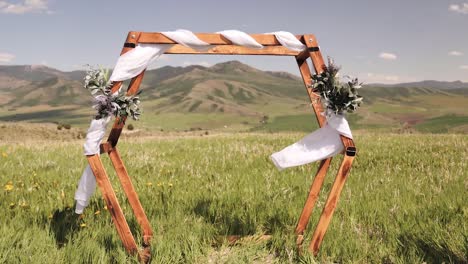 Hochzeitszeremonie,-Sechseckiger-Bogen-Aus-Holz,-Bedeckt-Mit-Blumen-Und-Weißem-Leinen,-Der-Im-Wind-Weht,-In-Den-Bergen-Von-Idaho-Für-Ein-Kleines-Elopement-1080p-60fps