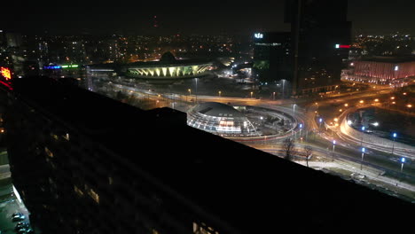 Vista-Aérea-Del-Centro-De-Katowice,-La-Rotonda-Generała-Ziętka-Y-El-Edificio-De-Apartamentos-Superjednostka-En-Primer-Plano,-En-La-Noche