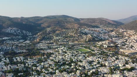 aerial-view-of-Bodrum-valley-filled-with-white-villas-as-the-sun-sets-over-the-hills-and-homes-in-Mugla-Turkey-on-a-sunny-summer-afternoon
