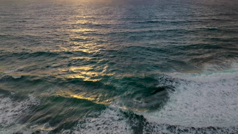 Sunset-reveal-from-drone-as-waves-crash-near-shore-of-gorgeous-beach-in-Mexico