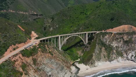 Wide-aerial-view-of-Bixby-Creek-Bridge-on-a-sunny-summer-day-in-Big-Sur-California-with-the-white-sand-beach-below