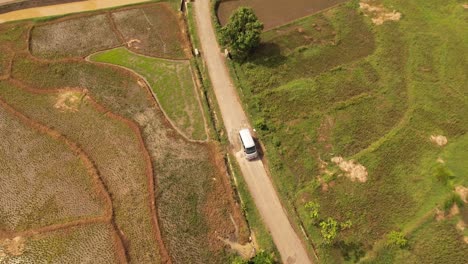 Aerial-shot-of-car-riding-through-empty-rural-road