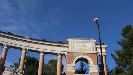 Italienische-Flagge-Weht-Im-Wind---Antikes-Denkmal-Und-Sonniger-Blauer-Himmel-Im-Hintergrund