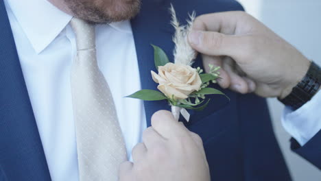 Best-man-fixing-boutonniere-on-groom's-lapel-wedding-preparation