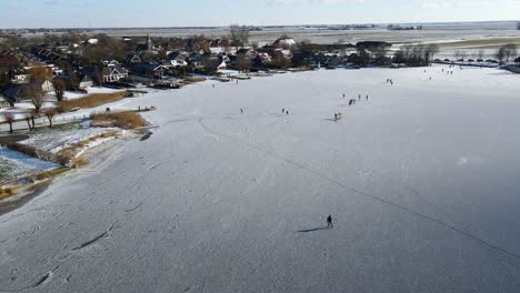 Drone-shot-of-people-ice-skating-themselves-on-a-frozen-lake-in-The-Netherlands