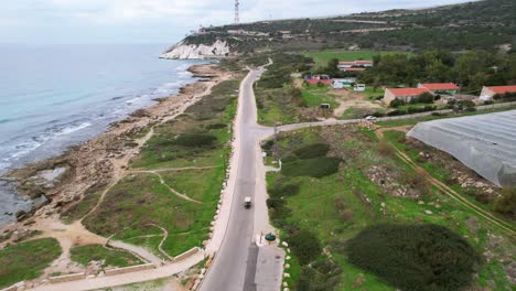 Drone-shot-following-a-Golf-Car-driving-on-a-road,-filmed-in-Rosh-Hanikra,-Israel