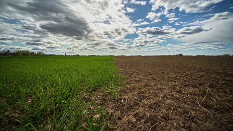Rolling-Clouds-Over-Rural-Field-With-Green-Grass-And-Brown-Soil