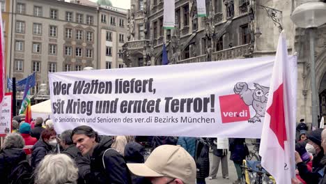 Menschen-Halten-Während-Einer-Antikriegsdemonstration-In-München,-Bayern,-Deutschland-Ein-Transparent-Mit-Der-Aufschrift-„Waffenlieferungen-Säen-Krieg-Und-Ernten-Terror“