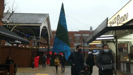 British-high-street-shoppers-passing-colourful-market-town-centre-Christmas-tree