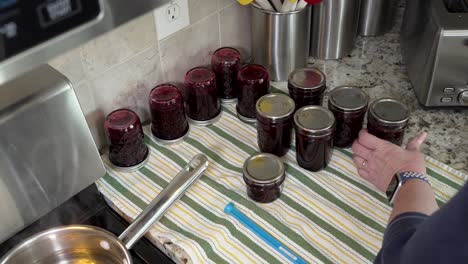 Screwing-the-lids-over-the-canning-seals-and-turning-the-jars-of-fresh-jam-upside-down-to-cool
