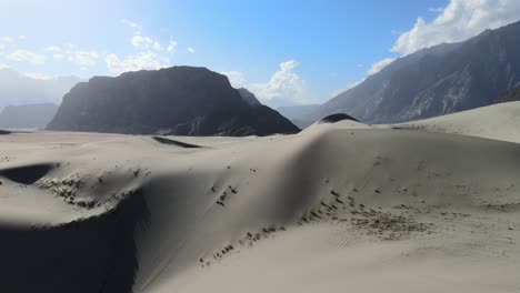 Drone-Aéreo-Volando-Sobre-Una-Duna-En-El-Desierto-Frío-De-Skardu-Pakistan-En-Un-Día-Soleado-De-Verano-Con-Grandes-Montañas-En-El-Fondo