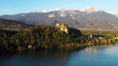 Drone-footage-of-Bled-Castle-or-Blejski-grad-in-Slovenia,-with-lake-Bled-in-the-foreground-and-the-Karawanks-Mountains-in-the-distance