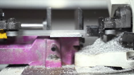 Automatic-saw-machine-cutting-a-metal-plate-leaving-metallic-sawdust